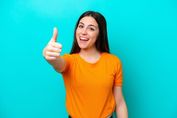 Young caucasian woman isolated on blue background with thumbs up because something good has happened