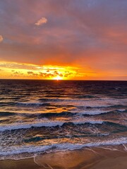 Obraz premium Fiery pre-sunrise peaking through the clouds lighting up the ocean