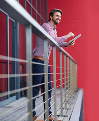Business, man and happy with tablet in balcony at office on break for social media interaction and...