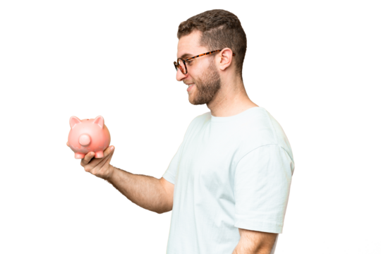 Young man holding a piggybank over isolated chroma key background with happy expression