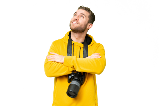 Young photographer man over isolated chroma key background looking up while smiling