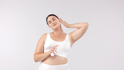 Obraz premium Young, beautiful brunette with curvy figure using skincare products on a white background. Perfect for promoting skincare, emphasizing confidence and beauty with your products.