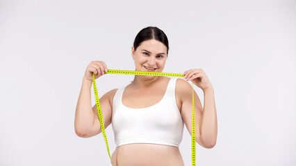 Woman measuring her body on a light background after a workout. Perfect for promoting weight loss, showcasing results, and motivating progress towards fitness goals.