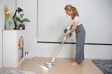 Fototapeta premium Woman Cleaning Floor with Modern Vacuum Cleaner in Stylish Room with Minimalist Decor and Indoor Plants