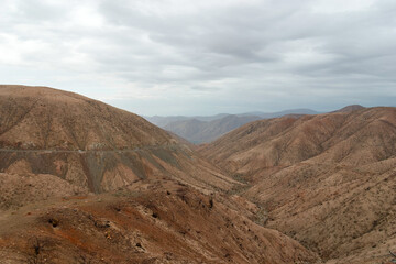 Winding road is carving its way through a barren desert landscape. Showcasing the rugged beauty of nature's artistry. The vast expanse of arid hills and valleys creates a sense of solitude and awe