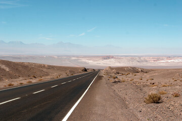 Endless asphalt road disappearing into the horizon in the middle of the driest desert in the world,...