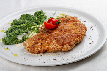 Chicken schnitzel served with sauce, accompanied by broccoli and cheese fritters.