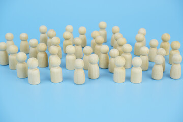 Many wooden figures standing close to each other on blue background.