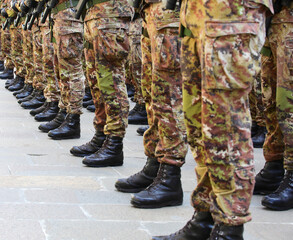 Black combat boots of army soldiers in camouflage uniforms standing in formation
