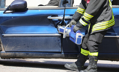 Fototapeta premium Firefighter uses industrial shears called Jaws of Life to extricate injured from crashed car