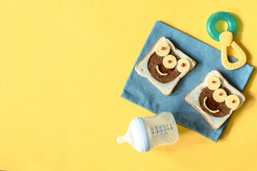 Funny monster face on halloween sandwich toast bread with peanut butter,cheese. Kids child sweet dessert breakfast lunch food menu on yellow background copy space.