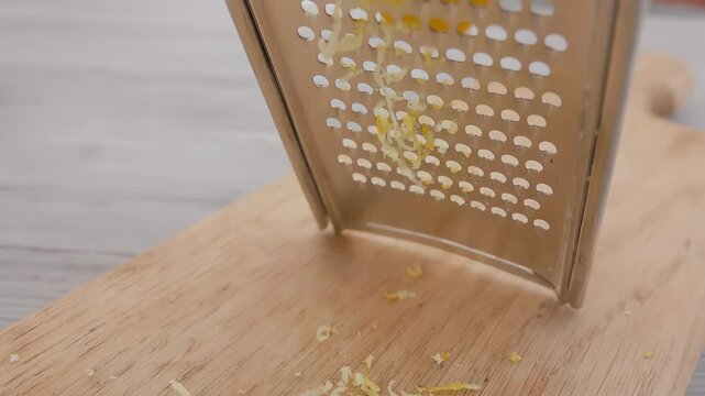 Close-up of a lemon grated on the metal grater into the lemon zest in slow motion. High quality 4k footage