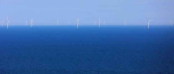 offshore white wind turbines in the middle of the sea for the production of clean electricity by...