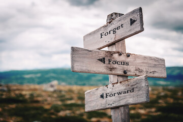 forget focus forward text quote on wooden directional signpost outdoors in nature