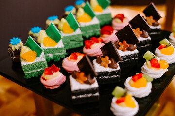 Hundreds of colorful, cute-shaped sweet pastries displayed on a table, ready to be served to guests.