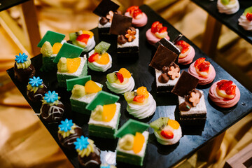 Hundreds of colorful, cute-shaped sweet pastries displayed on a table, ready to be served to guests.