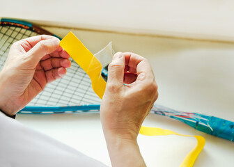 woman replaces old winding on handle of racket with new one. racket grip replacement process