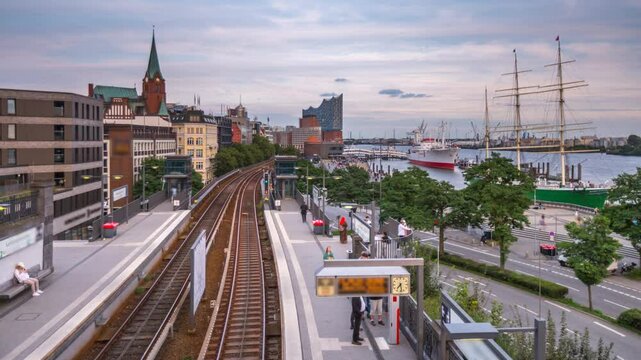 Hamburg city busy subway station (Landungsbruecken) at the waterfront. Tourists and commuters walking and boarding trains on a sunny day with city view in the background 4K footage.