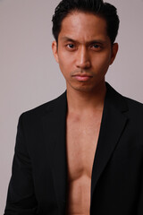 Thoughtful young asian man posing over white background. Vertical headshot.