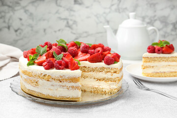 Tasty sponge cake with fresh berries and mint on light gray table