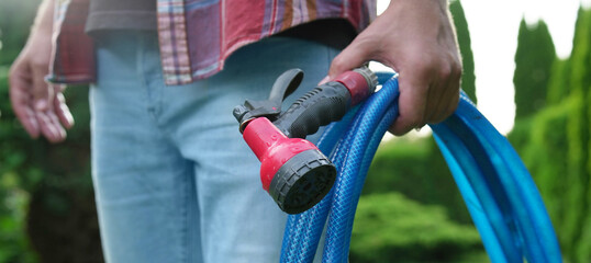 Man holding watering hose with sprinkler in garden, closeup