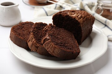 Delicious cut chocolate sponge cake on white tiled table, closeup