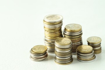 Stacks of euro coins on white textured table, closeup
