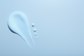 Sample of face cream on light blue background, top view. Space for text