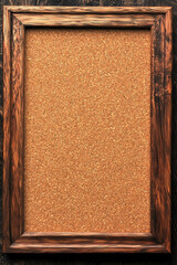 Fototapeta premium Empty rustic wooden frame with corkboard on dark wooden background. Perfect for displaying s, notes, or creative projects.