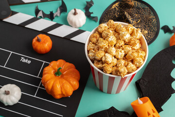 Movie clapperboard and Halloween decorations with popcorn on green background, theater and pumpkin...