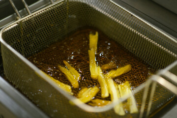 Golden fries cooking in a deep fryer at a hotel kitchen