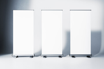 Three blank roll-up banners in a studio with gradient background. 3D Rendering