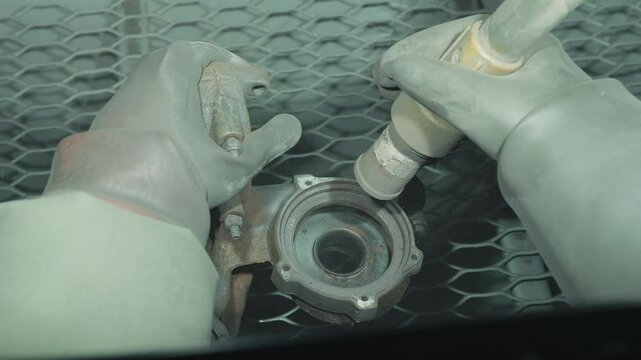 Close up cleaning and removing rust from car detail using a sandblasting machine