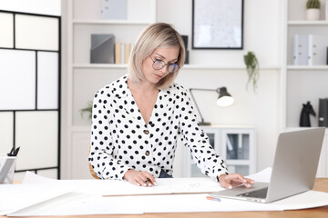 Architect making engineering drawing at table in office