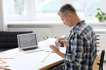 Obraz premium Architect making digital engineering drawing on tablet at table in office