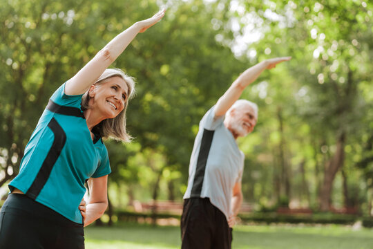 Senior couple stretching together outdoors in park, outdoors