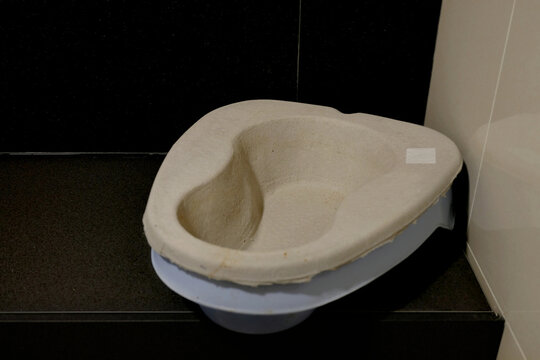 A single use or disposable bedpan on a hospital bathroom counter top for patients to relief themselves. Cardboard or pulp material made. Throw away urinal pan to avoid cross contamination.