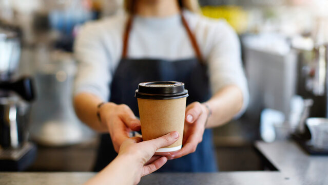Coffee to go in hand of barista in coffee shop