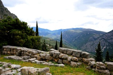 Ancient Greek ruins of the temple complex of the Oracle of Delphi in Greece with a breathtaking view of the panorama of the Pleistos River valley on a sunny summer's day  © Thomas