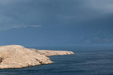 Landscape with wavy sea and dark stormy clouds above mountain Velebit in Dalmatia, dangerous weather