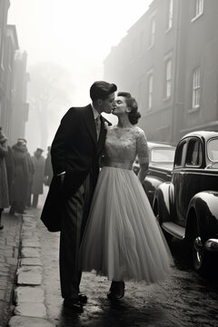 Fototapeta A romantic black-and-white vintage scene of a couple kissing in elegant wedding attire on a foggy street, evoking nostalgia with classic cars and bystanders watching.