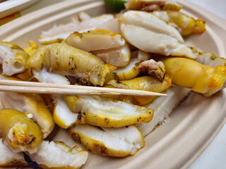 Grilled squid eggs with skewers on a plate closeup image