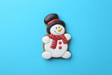 Tasty Christmas cookie in shape of snowman on light blue background, top view
