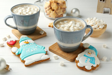 Delicious cookies in shape of snowmen, cups with cocoa and Christmas decor on white wooden table