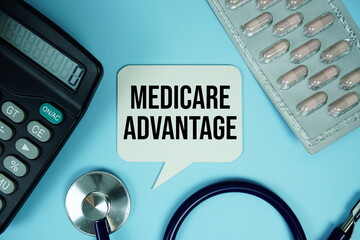 Medicare Advantage text on speech bubble with calculator and stethoscope top view on blue background