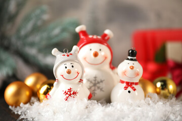 Funny snowmen figures and Christmas decor on table, closeup