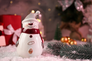 Funny snowman figure and fir branch on artificial snow, closeup