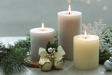 Burning candles, baubles and fir tree branches on white textured table, closeup