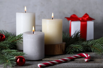 Burning candles, Christmas decor and fir tree branches on wooden table, closeup