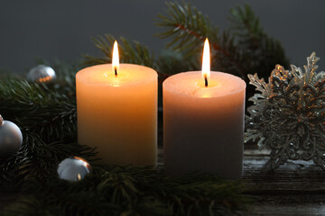 Burning candles, baubles and fir tree branches on wooden table, closeup